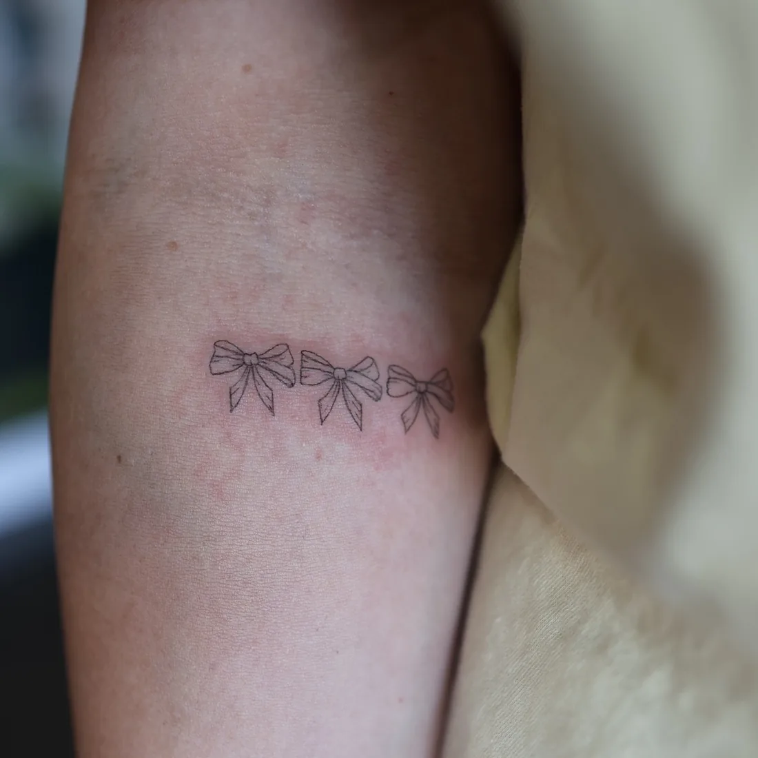 A dainty fine line bow on an inner arm.