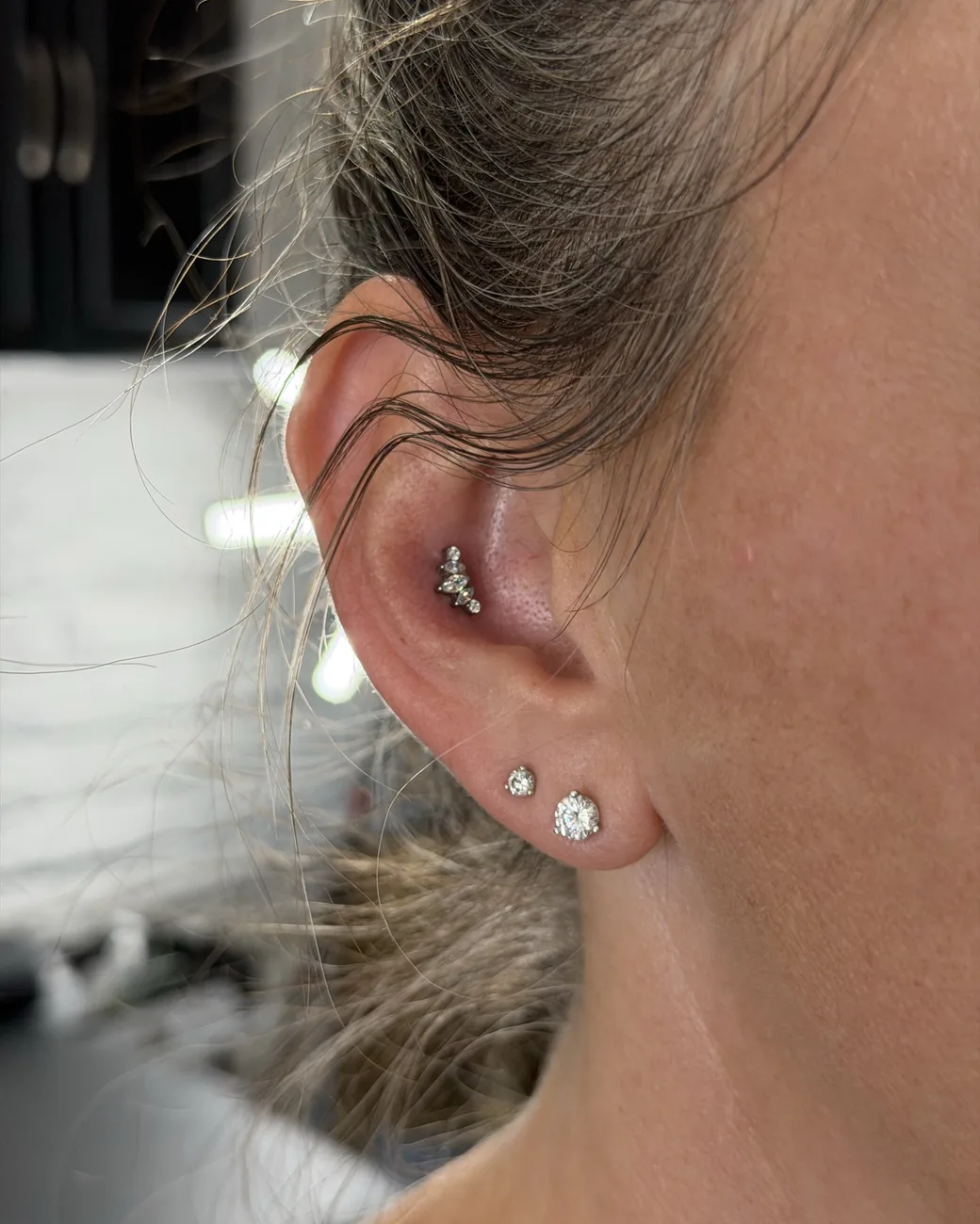 A helix cluster of gold and stone studs above stacked lobes.