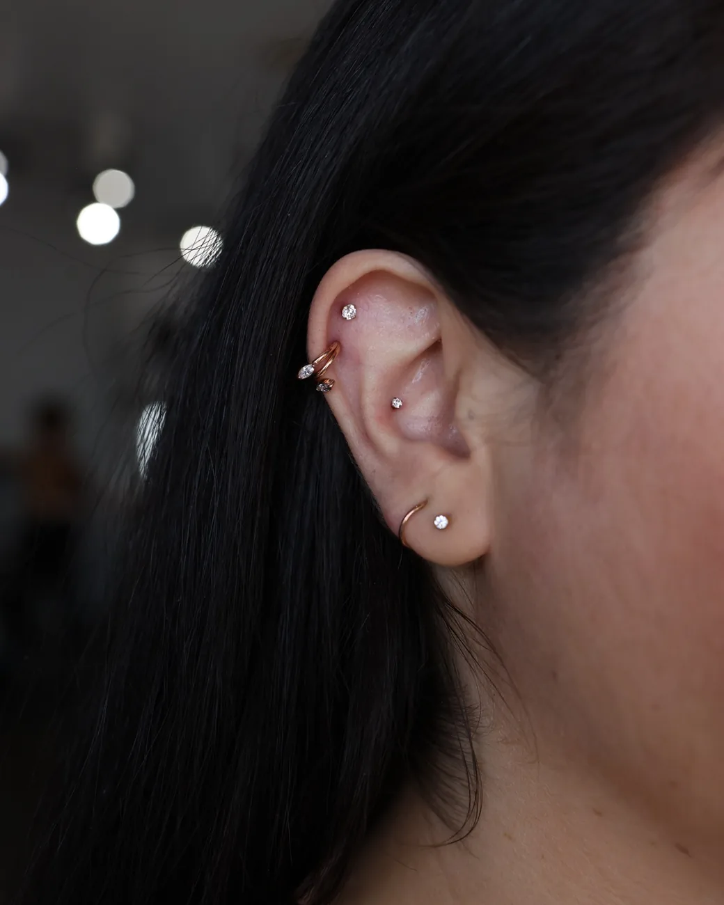 Stacked lobe piercings in fine gold hoops and studs.