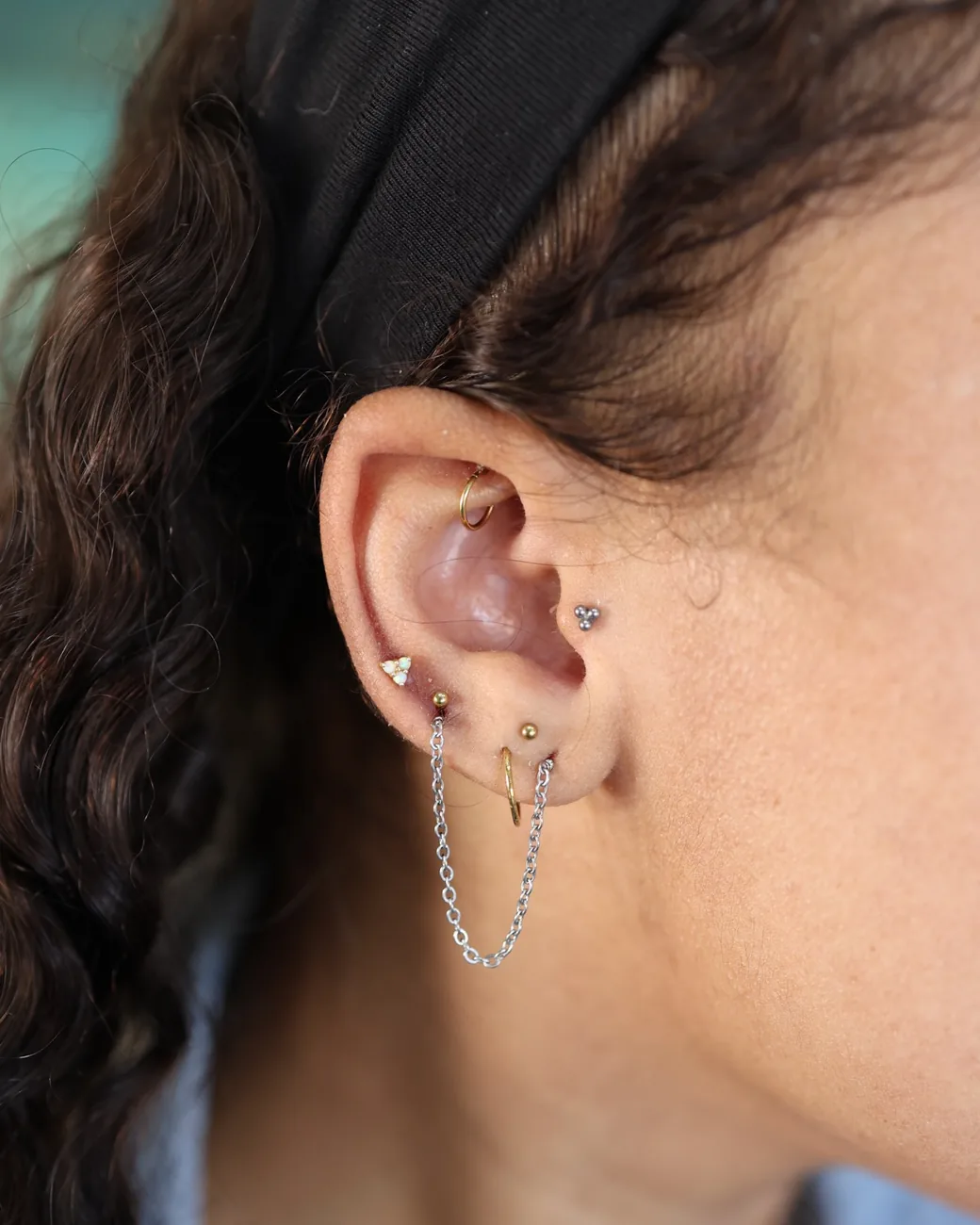 A fine gold chain connecting two healed lobe piercings.