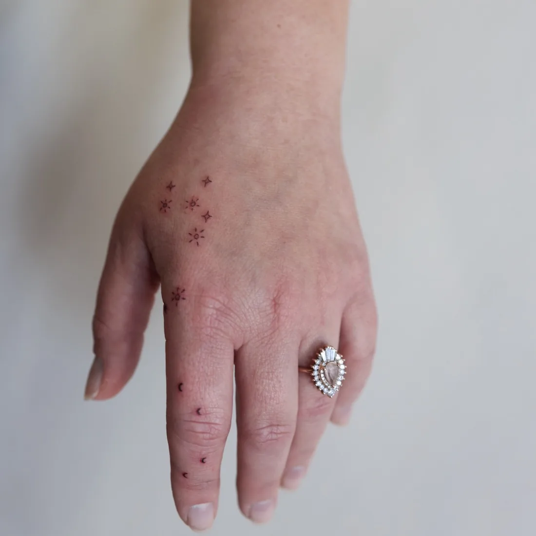 Scattered fine line stars across the back of a hand.