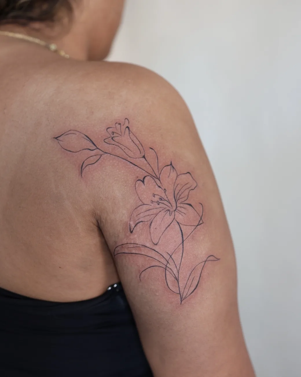 A fine line lily flowing across a shoulder.