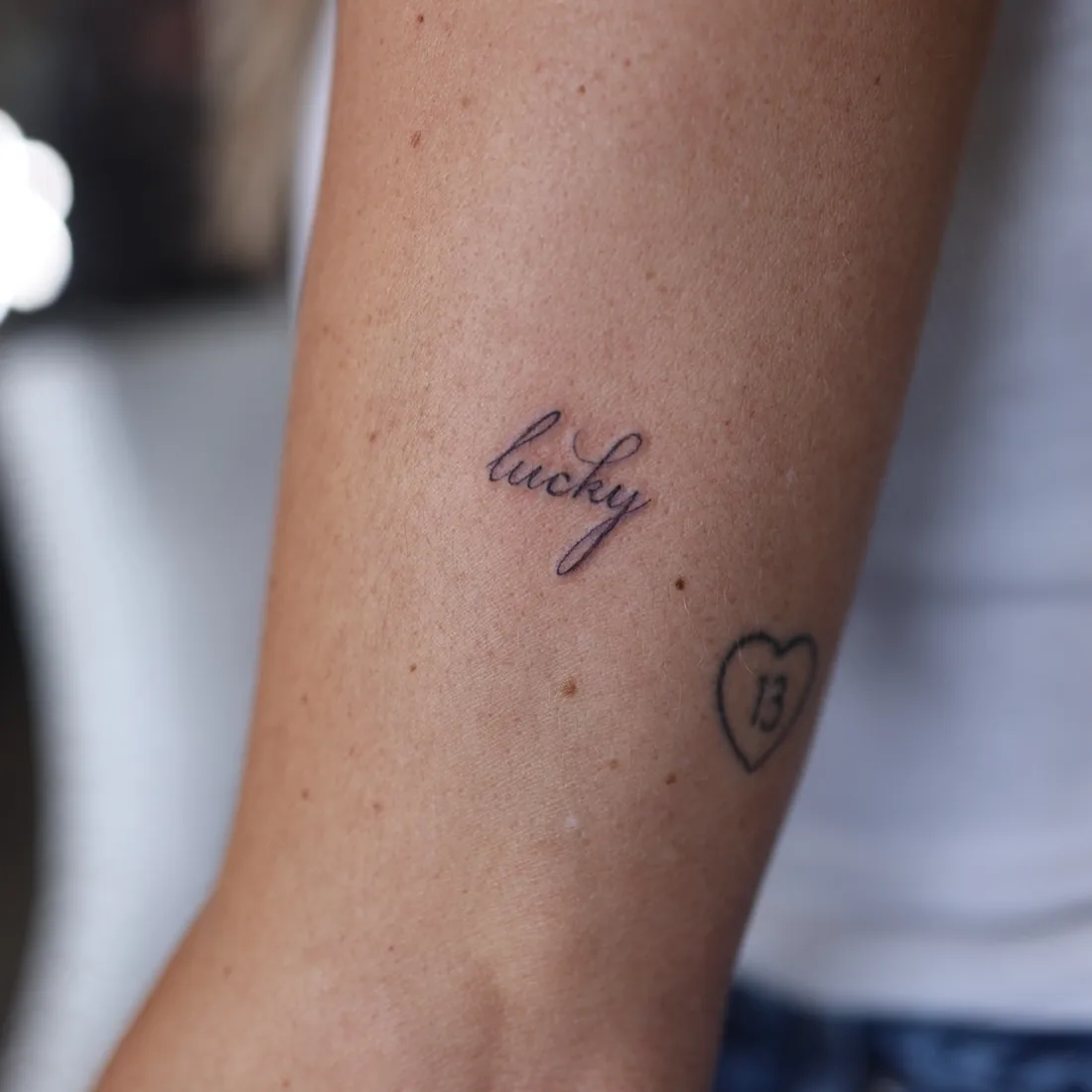 The word lucky in fine line script on an inner arm.