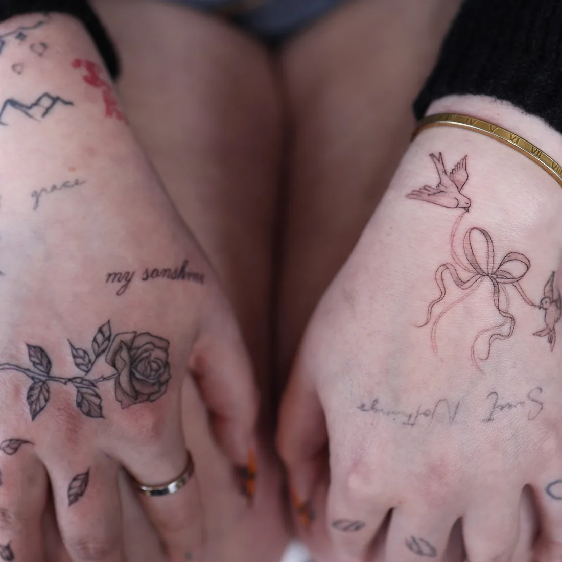 Fine line roses, bows and script across the backs of both hands.